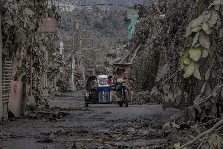 A tricycle drives along a road covered in volcanic ash from Taal Volcano’s eruption on Jan. 14, 2020 in Talisay, Batangas province, Philippines.