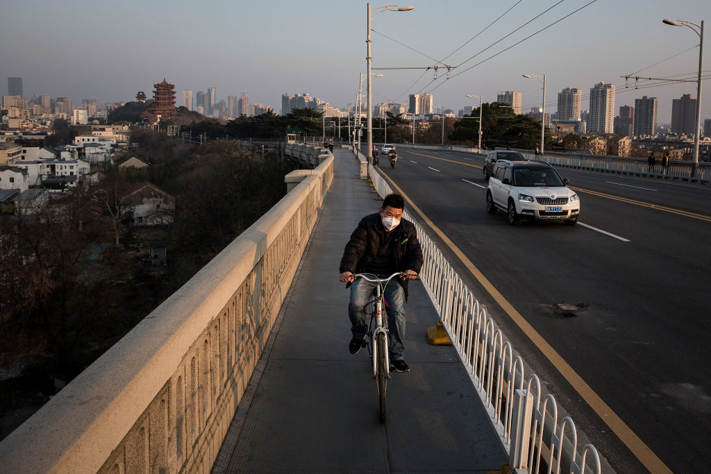 A man wears a protective mask as he rides a bicycle across the Yangtze River Bridge on Jan. 31, 2020 in Wuhan, China.
