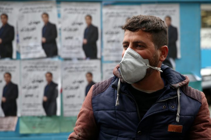 A man stands in front of parliamentary election campaign posters in Tehran, Iran, Feb. 20, 2020. 