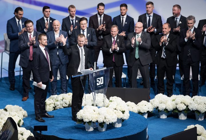 Former Vancouver Canucks players Henrik Sedin, front right, and his twin brother Daniel Sedin, left, both of Sweden, speak during a jersey retirement ceremony before an NHL hockey game in Vancouver, on Wednesday February 12, 2020.
