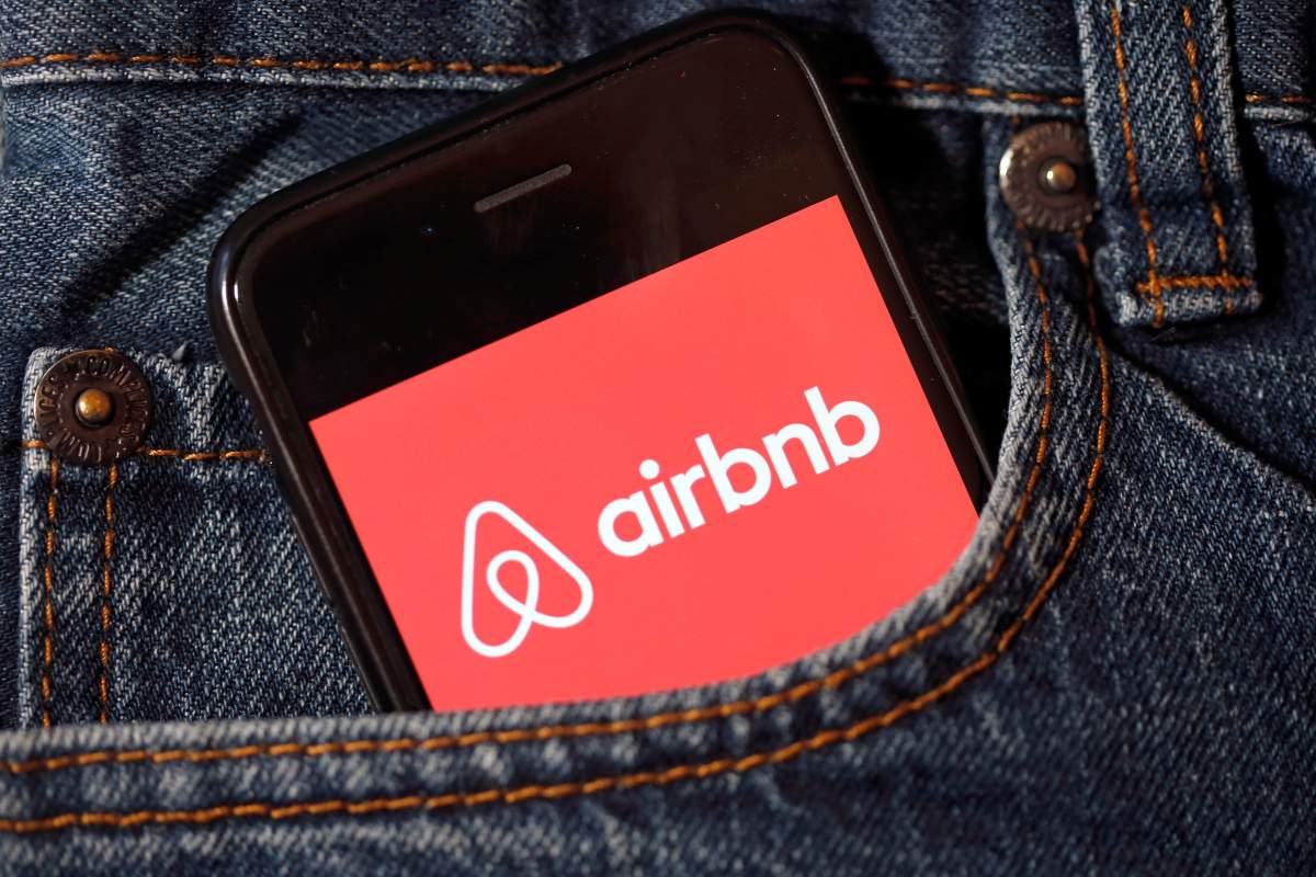 The Airbnb logo is displayed on a phone screen.