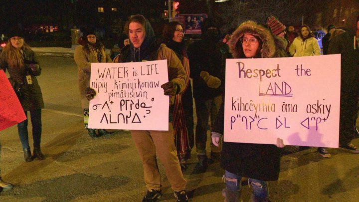 Regina protesters hold up signs reading “Water Is Life” and “Respect The Land”