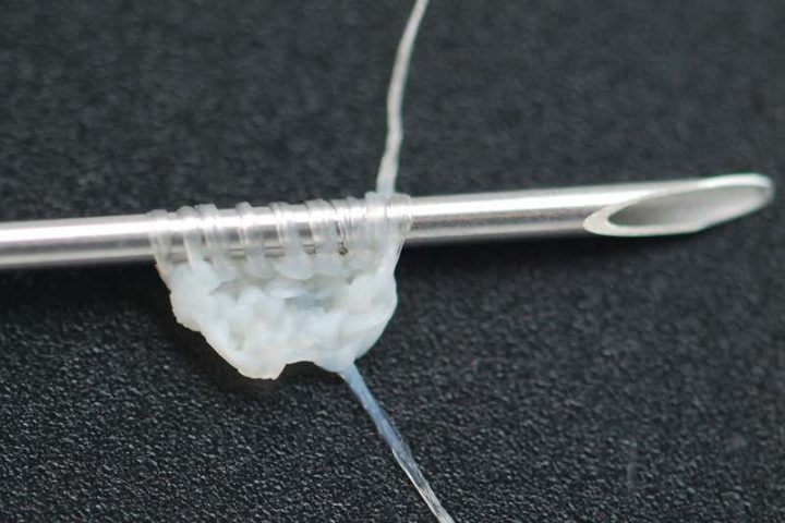 A stitched arrangement of yarn derived from human cells is shown.