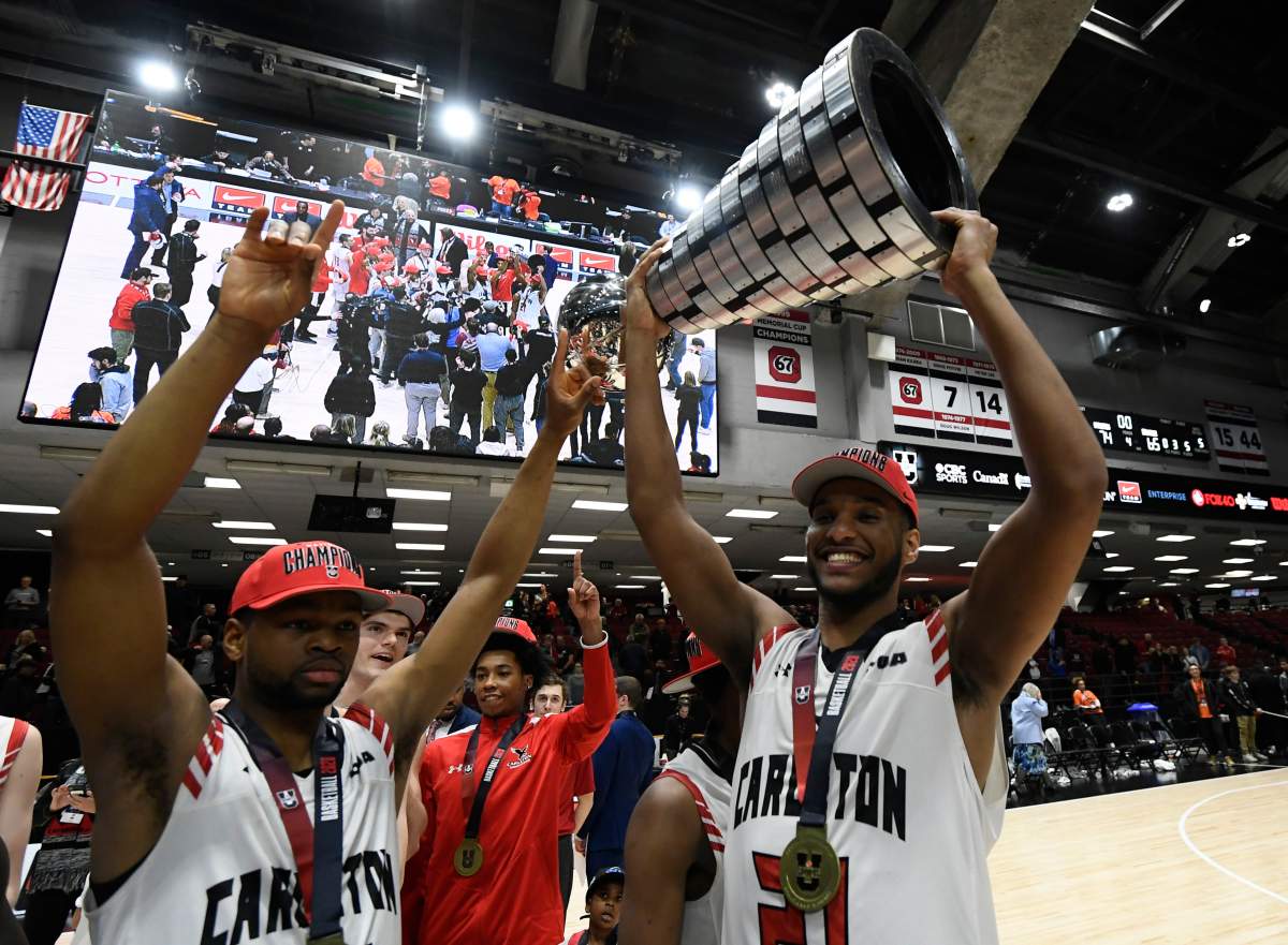 Carleton University Ravens’ Biniam Ghebrekidan (21) raises the trophy as forward Lloyd Pandi (41) raises his hands as the team celebrates their win over the Dalhousie Tigers in men’s championship final basketball game of the U Sports Final 8 Championships, in Ottawa, on Sunday, March 8, 2020.