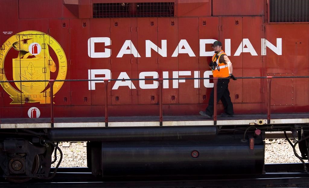 A Canadian Pacific Railway employee walks along the side of a locomotive in a marshalling yard in Calgary, Wednesday, May 16, 2012.