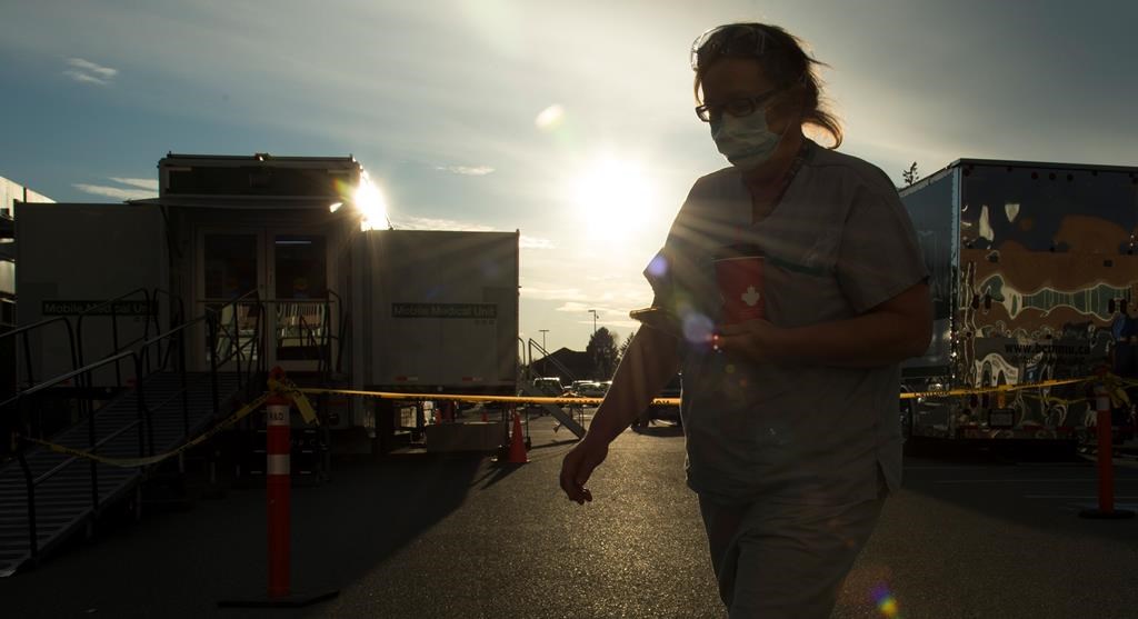 A health-care worker is silhouetted as they walk past the British Columbia mobile medical unit set up outside of Abbotsford Regional Hospital in Abbotsford, B.C. Tuesday, April 14, 2020. The mobile medical unit was deployed to Abbotsford to assist with the COVID-19 outbreak that has occurred at the Mission Correctional Institution.