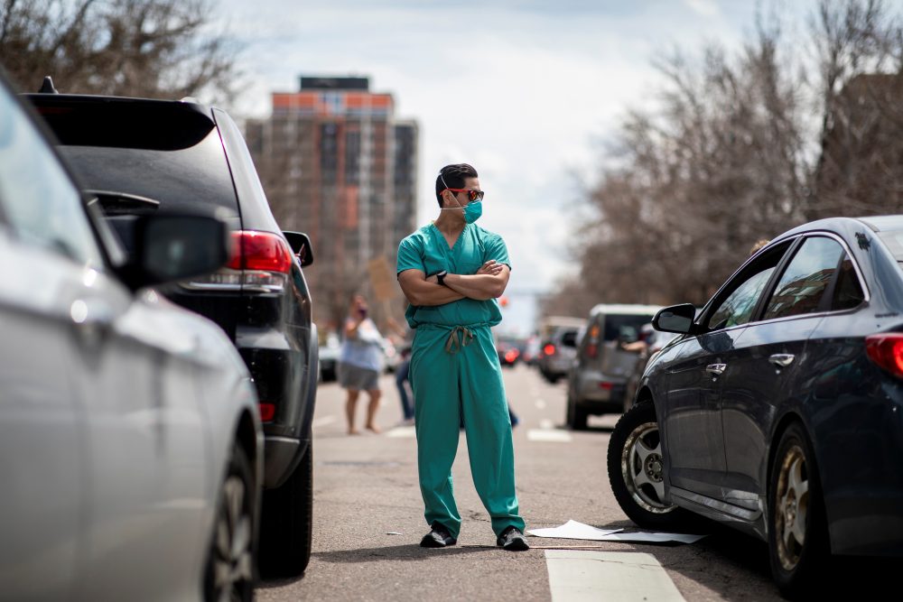 Health-care workers stand in the street in counter-protest to hundreds of people who gathered at the State Capitol to demand the stay-at-home order be lifted in Denver, Colo., on April 19, 2020.