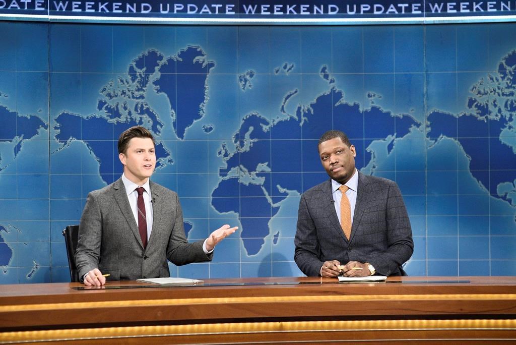 This Feb. 29, 2020 photo released by NBC shows Colin Jost, left, and Michael Che during the Weekend Update sketch on "Saturday Night Live" in New York. The show will be back on the air this weekend with a show that abides by social distancing rules. NBC says the comedy sketch show will include include a “Weekend Update” news segment and original content from “SNL” cast members. The material will be produced remotely, in compliance with efforts to limit the spread of the coronavirus. (Will Heath/NBC via AP).