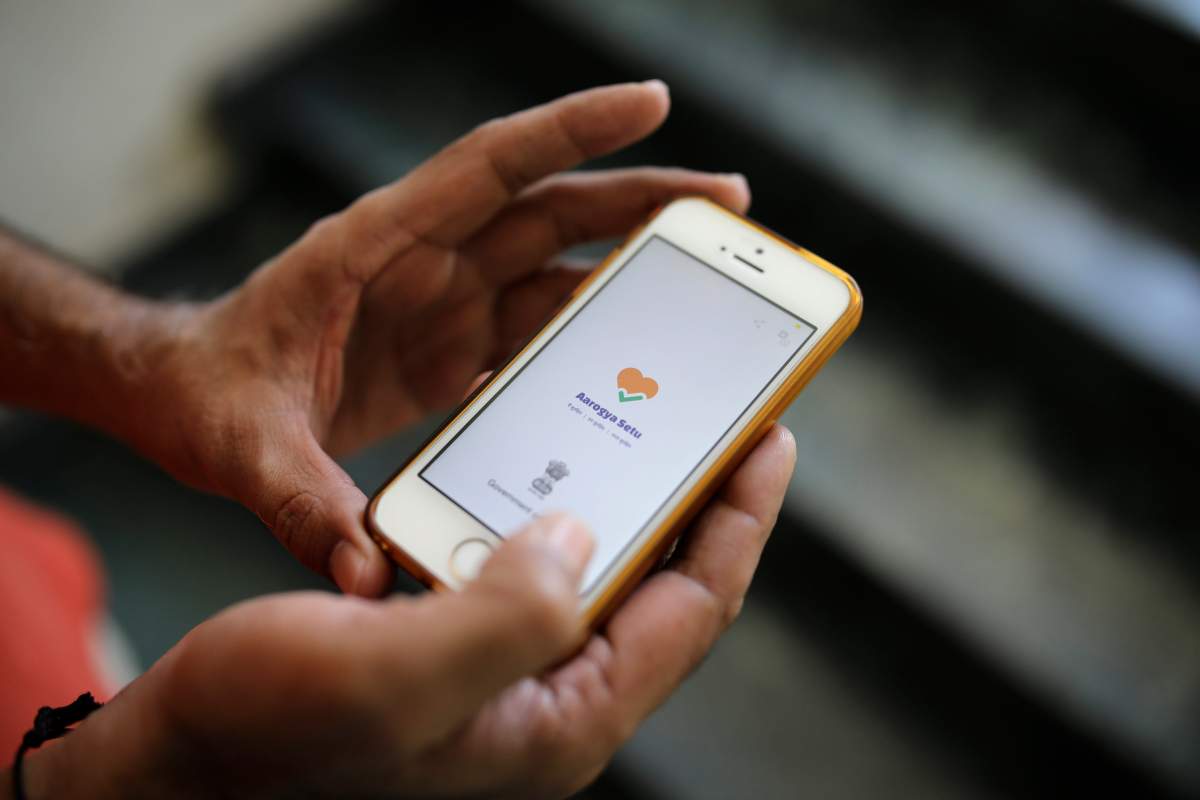In this Thursday, May 7, 2020 photo, an Indian man uses Aarogya Setu app on his mobile phone in New Delhi, India.