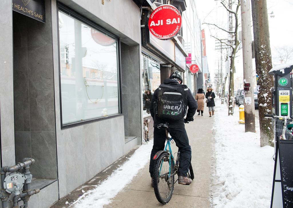 An Uber Eats courier is pictured as they pick up an order for delivery from a restaurant in Toronto, Thursday, Feb. 27, 2020.