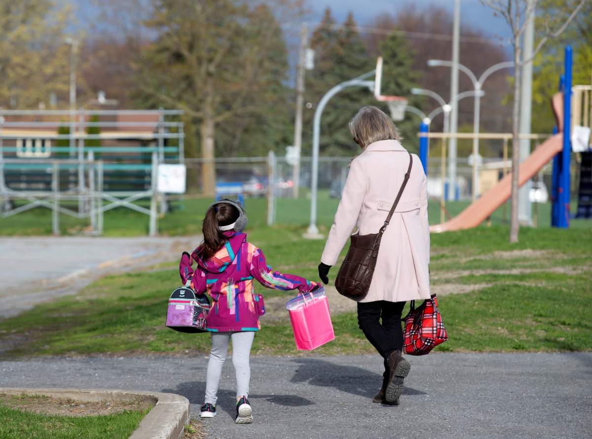 FILE PHOTO: A student is escorted into the schoolyard by a teacher.