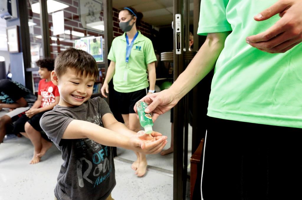 Bruce McCall, 5, smiles as he takes hand sanitizer during martial arts daycare summer camp at Legendary Blackbelt Academy in Richardson, Texas, Tuesday, May 19, 2020.
