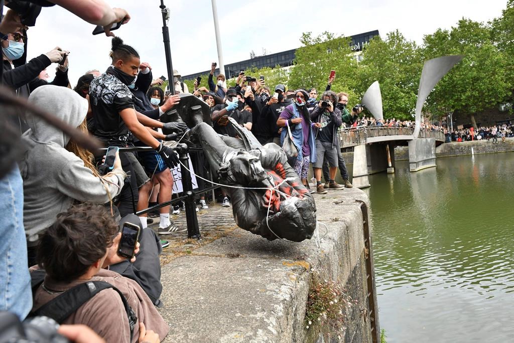 Protesters throw a statue of slave trader Edward Colston into Bristol Harbour during a Black Lives Matter protest rally in Bristol, England, Sunday, June 7, 2020, in response to the recent killing of George Floyd by police officers in Minneapolis, which has led to protests in many countries and across the U.S. (Ben Birchall/PA via AP)