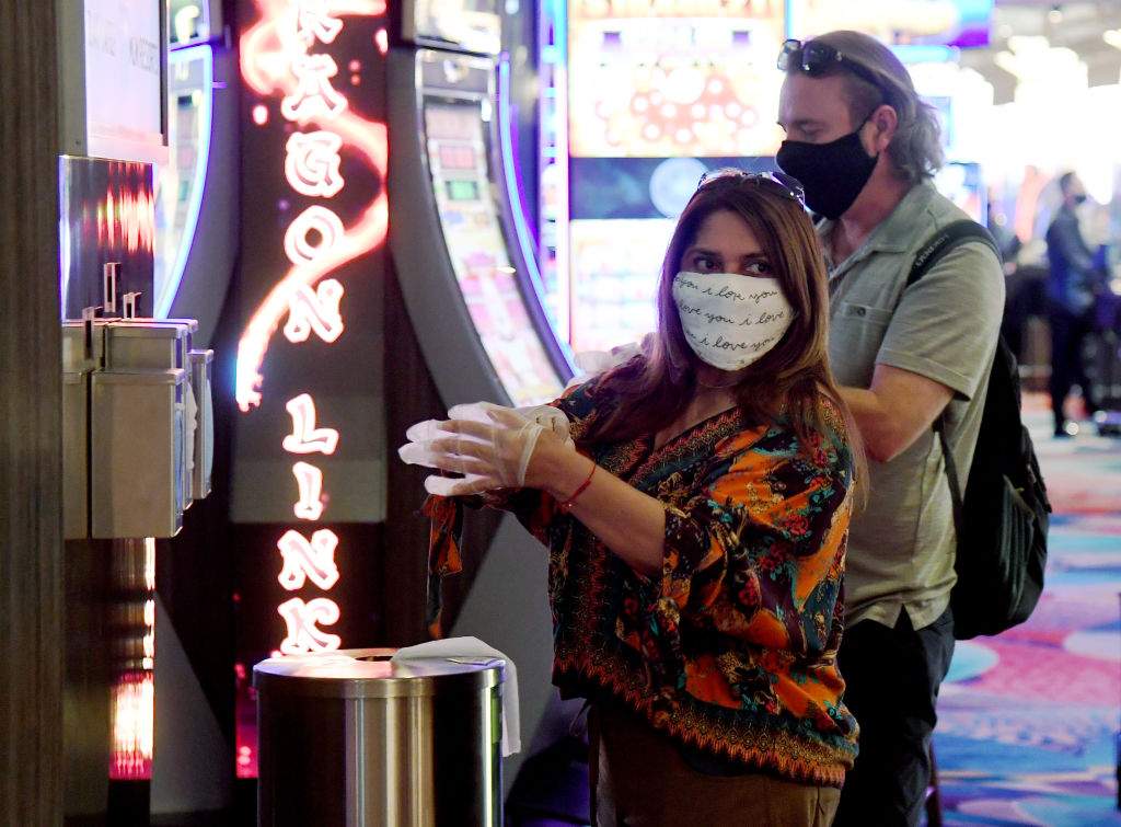 Guests take complimentary gloves from the side of a new hand-washing station on the gaming floor that also offers masks and wipes at Bellagio Resort & Casino on the Las Vegas Strip after the property opened for the first time since being closed on March 17 because of the coronavirus (COVID-19) pandemic on June 4, 2020 in Las Vegas, Nevada.