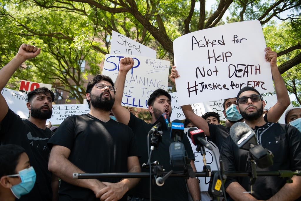 Khizar Shahzad, left, Hashim Choudhary, second from left, and Hassan Choudhary, centre, shout for justice at the end of a press conference in front of the apartment building where their uncle, Ejaz Choudry, 62.