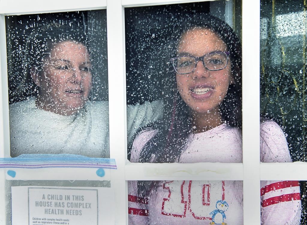 Lisa Ali and her 15-year-old daughter Tahlia look out from the front door of their Halifax-area home in Cole Harbour, N.S., on March 24, 2020.