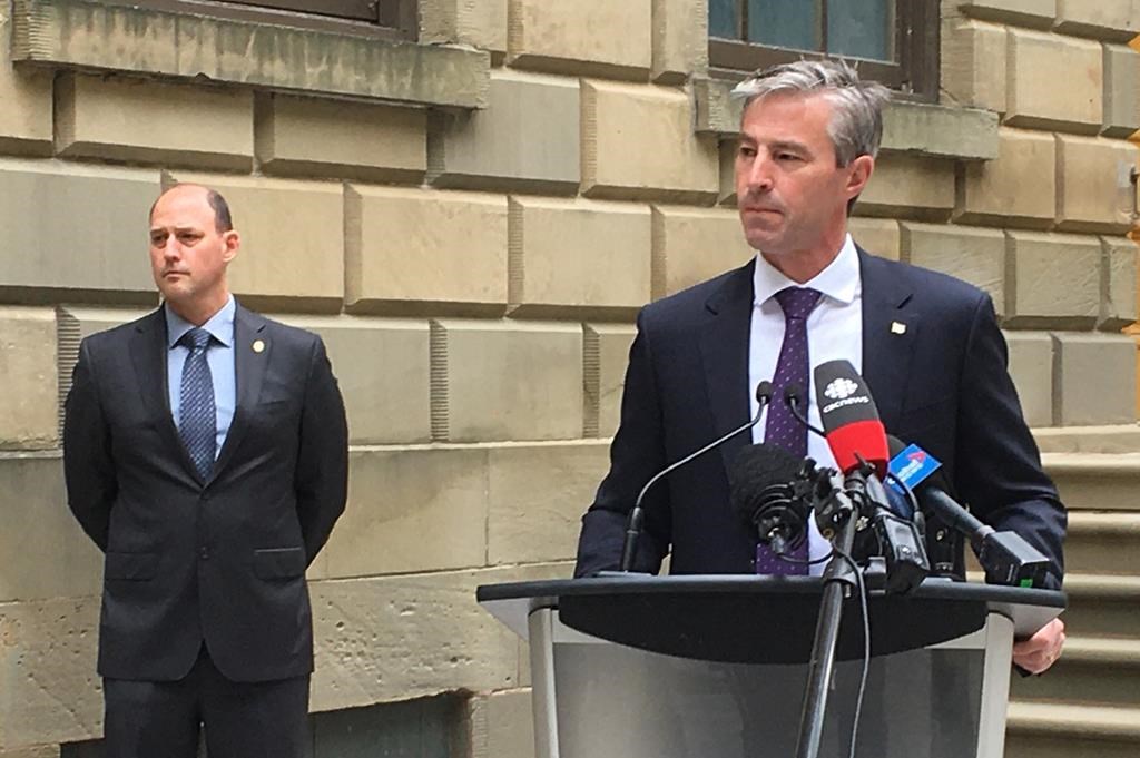 Nova Scotia Progressive Conservative Leader Tim Houston takes questions from reporters, Wednesday, June 24, 2020 outside the provincial legislature in Halifax as party education critic Tim Halman looks on. THE CANADIAN PRESS/Keith Doucette.