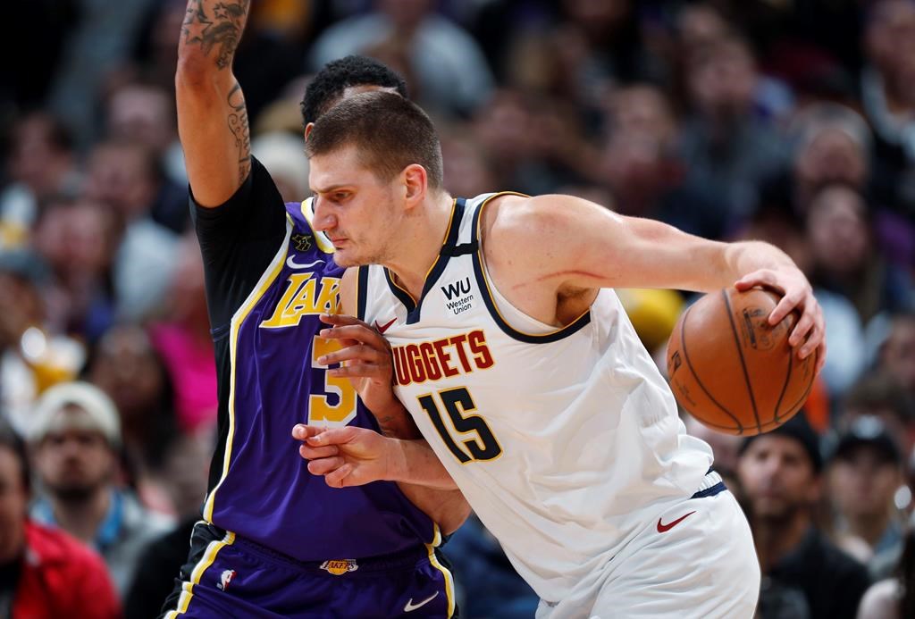 FILE - In this Feb. 12, 2020, file photo, Denver Nuggets center Nikola Jokic drives as Los Angeles Lakers forward Anthony Davis defends during the first half of an NBA basketball game in Denver. A person with knowledge of the situation says Jokic has tested positive for the coronavirus and is quarantining in his native Serbia. (AP Photo/David Zalubowski, File).