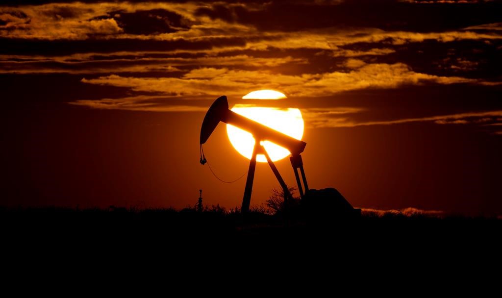 The sun sets behind an idle pump jack.