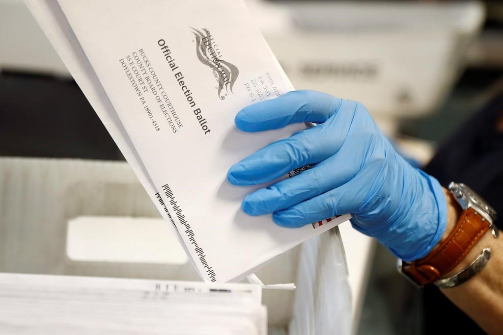 FILE - In this May 27, 2020 file photo, a worker processes mail-in ballots at the Bucks County Board of Elections office prior to the primary election in Doylestown, Pa. A network of deep-pocketed progressive donors are launching a $59 million effort to encourage people of color to vote by mail in November, a step many Democrats view as crucial to turning out the party's base during a global pandemic. (AP Photo/Matt Slocum, File).