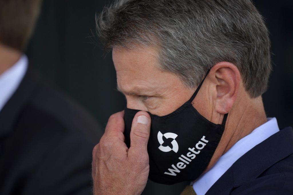 Georgia Gov. Brian Kemp adjusts his mask prior to a bill signing at Wellstar Kennestone Hospital where the hospital opened a new Emergency Room space, Thursday, July 16, 2020, in Marietta, Ga. Mayors in Atlanta and other Georgia cities deepened their defiance of Gov. Kemp on Thursday, saying they want their requirements for people to wear masks in public to remain in place, even after the Republican governor explicitly forbade cities and counties from mandating face coverings.