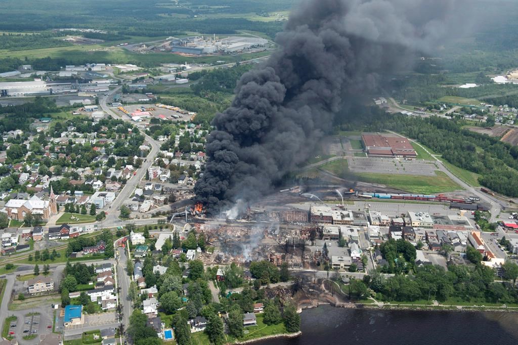 Smoke rises from railway cars that were carrying crude oil after derailing in downtown Lac-Mégantic, Que., Saturday, July 6, 2013. Lac-Megantic will mark the seventh anniversary of a tragic rail disaster that claimed 47 lives by inaugurating a long-planned memorial space.