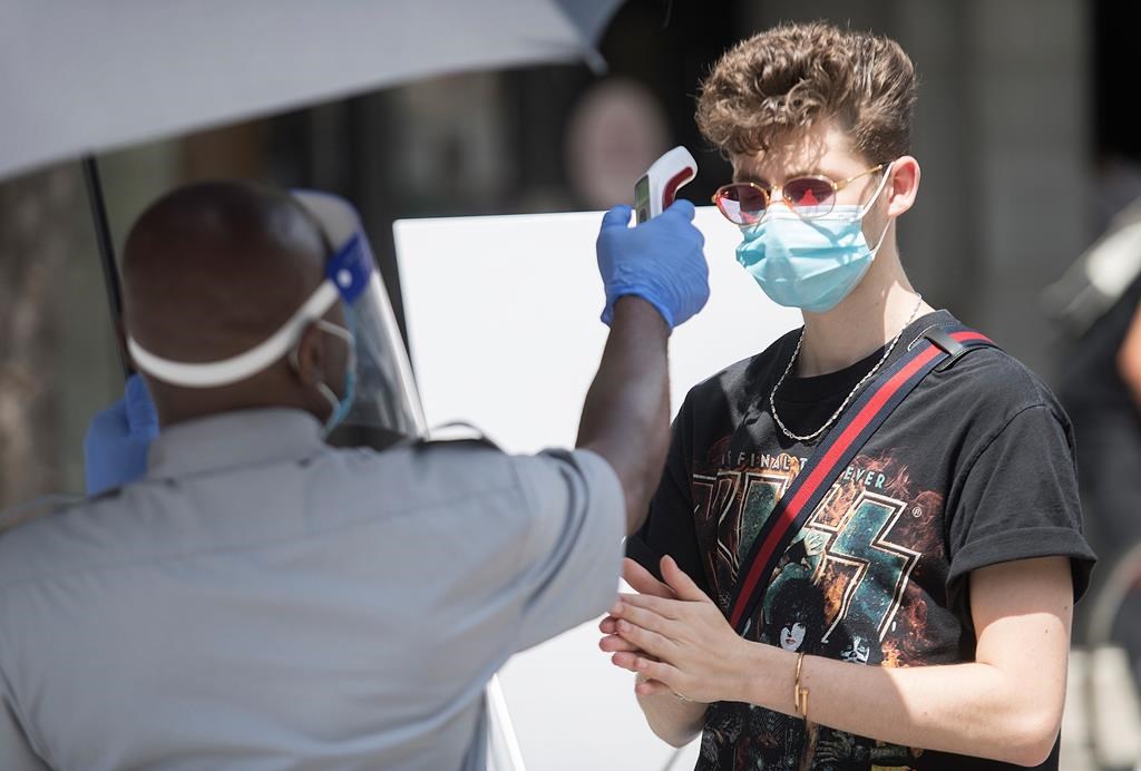 A man has temperature checked before entering a store in Montreal, Saturday, July 25, 2020.