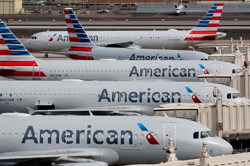  In this Wednesday, March 25, 2020, file photo, American Airlines jets sit idly at their gates as a jet arrives at Sky Harbor International Airport in Phoenix. 