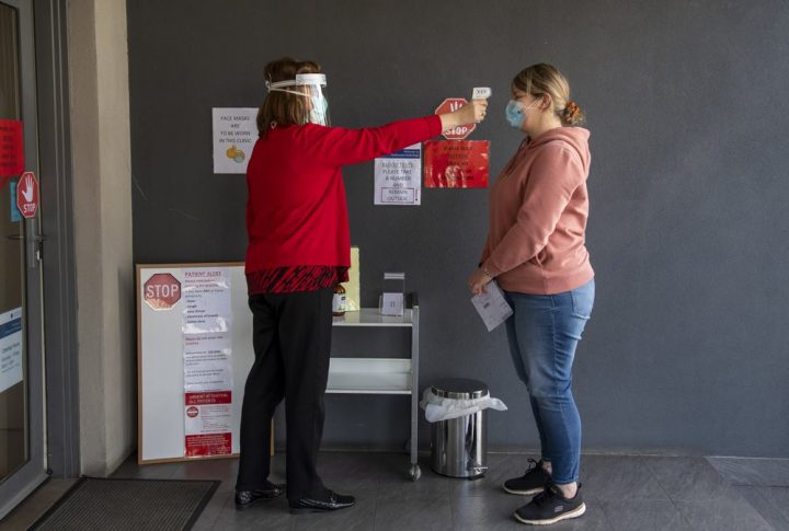 A patient has her temperature checked at a medical clinic during lockdown due to the continuing spread of the coronavirus in Melbourne, Thursday, Aug. 6, 2020. V=.