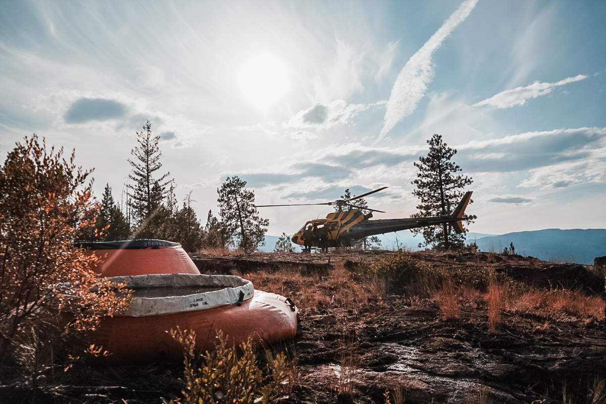 A helicopter landing beside some water bladders at the Christie Mountain wildfire near Penticton.