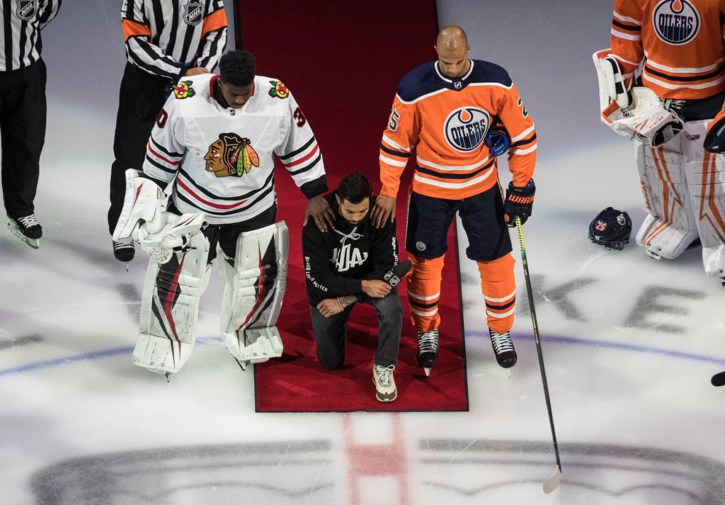 Minnesota Wild’s Matt Dumba takes a knee during the national anthem flanked by Edmonton Oilers’ Darnell Nurse, right, and Chicago Blackhawks’ Malcolm Subban before an NHL playoff game in Edmonton, Saturday, Aug. 1, 2020. THE CANADIAN PRESS/Jason Franson