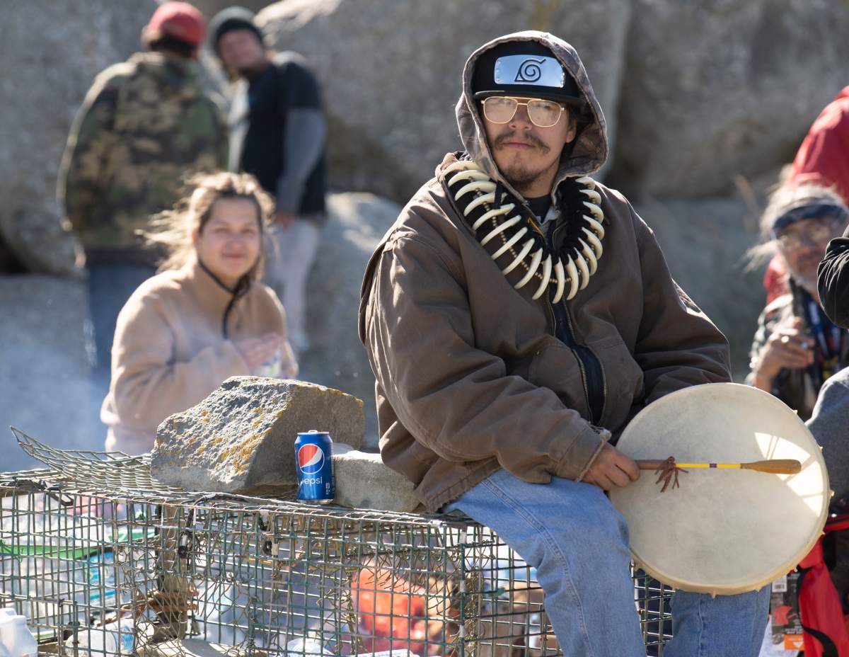 A Sipekne’katik First Nation community member holds a drum as he sits on lobster traps in Saulnierville, N.S., on Sept. 20, 2020. THE CANADIAN PRESS/Mark O’Neill