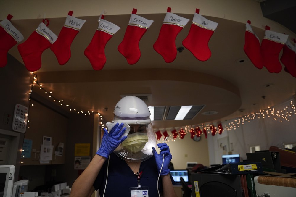 Registered nurse Romina Pacheco disinfects her powered air purifying respirator after tending to a patient in a COVID-19 unit decorated with Christmas stockings with nurses’ names written on them at Mission Hospital in Mission Viejo, Calif., Monday, Dec. 21, 2020.