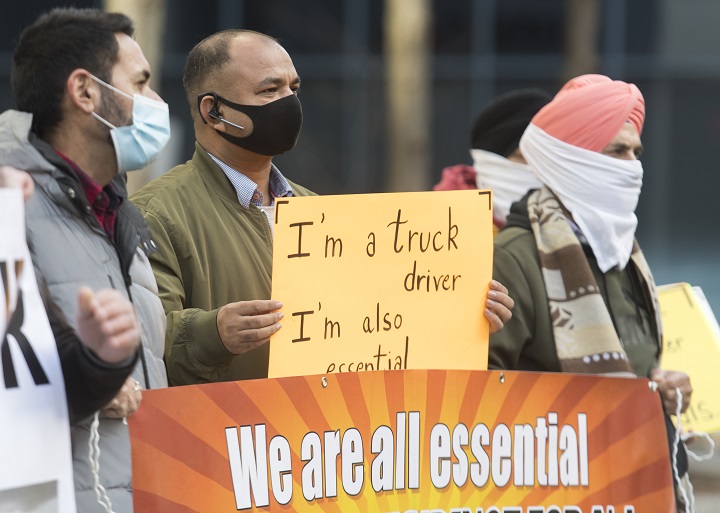 People take part in a demonstration outside Quebec Premier Francois Legault’s office in Montreal, Saturday, November 21, 2020, where they called on the government to give permanent residency status to all migrant workers and asylum seekers.