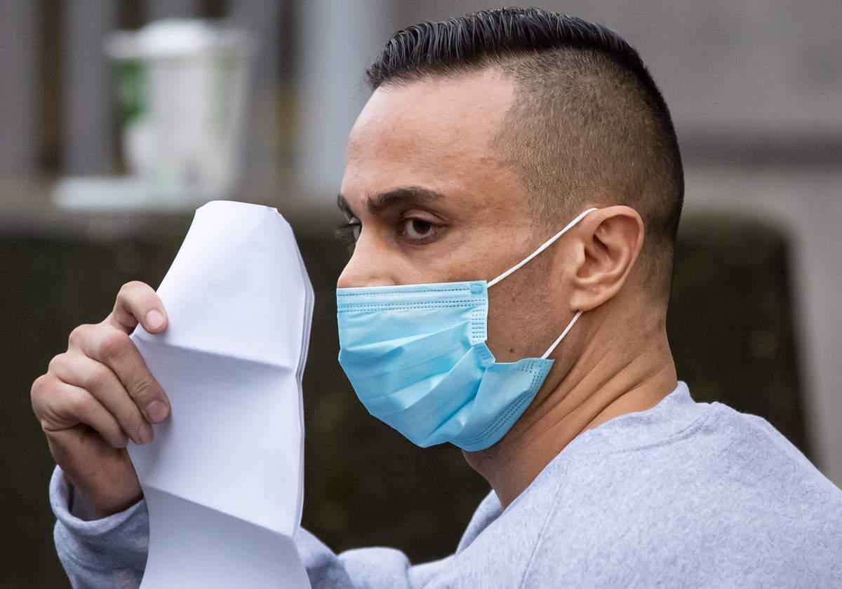 Mohammad Movassaghi tries to hide his face with a copy of his release order as he leaves Vancouver Police Department jail in Vancouver on Sunday, January 31, 2021. Police arrested a man who allegedly operated a makeshift nightclub at his Vancouver penthouse and issued fines against him and his suspected guests totalling more than $17,000.