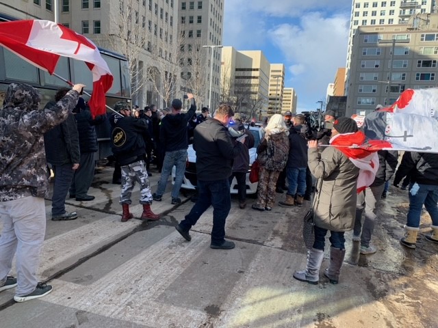 Protesters surround a police vehicle near the Alberta legislature in Edmonton on Saturday, Feb. 20, 2021.