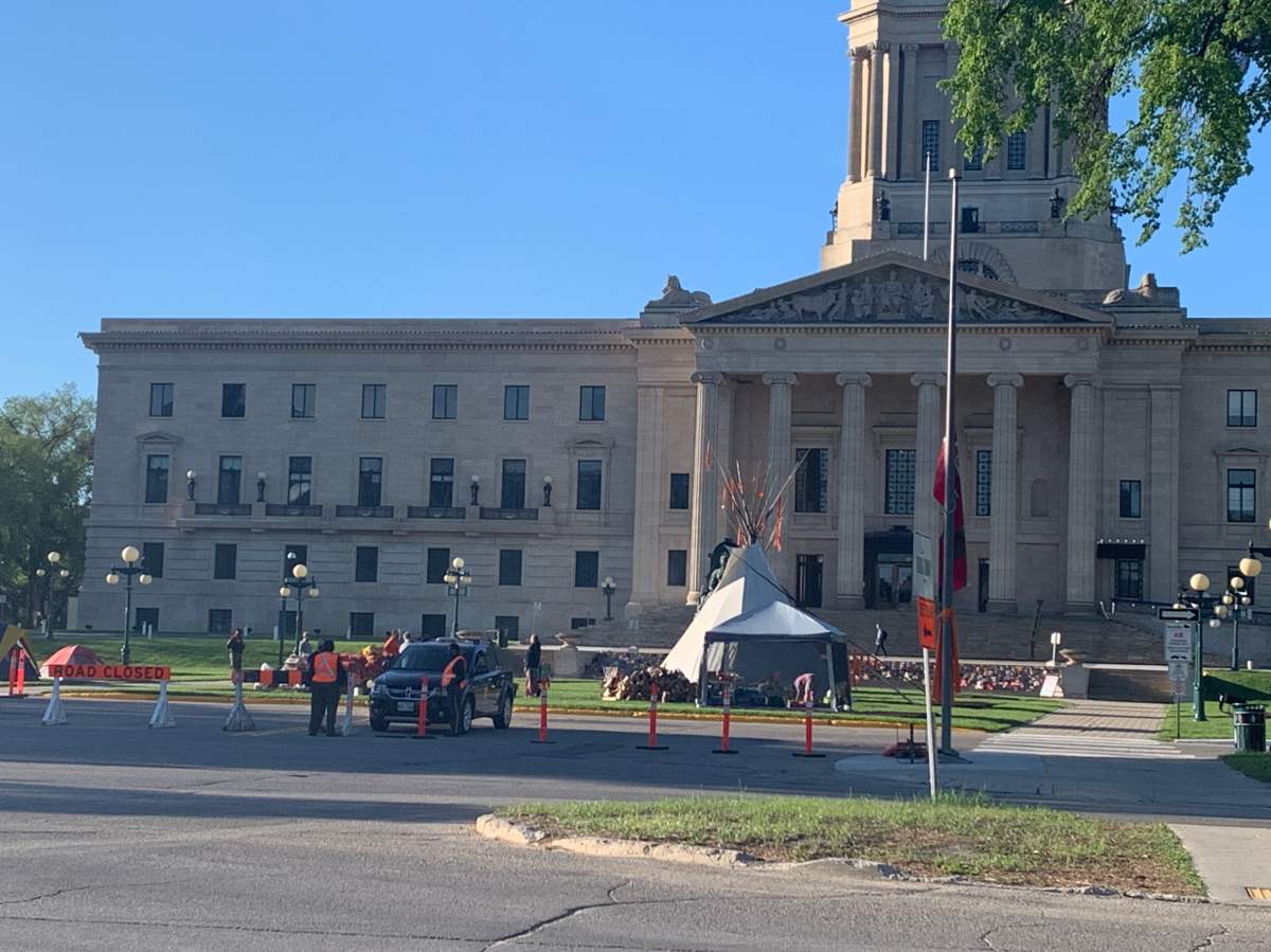 People gathered on the lawn of the Manitoba Legislative Building Monday morning, where hundreds of shoes representing 215 children who died at a Kamloops Residential School.