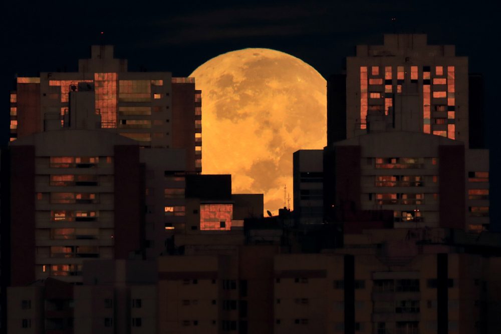The moon is partially covered by buildings in Brasilia, Brazil, at the start of a total lunar eclipse early Wednesday, May 26, 2021.