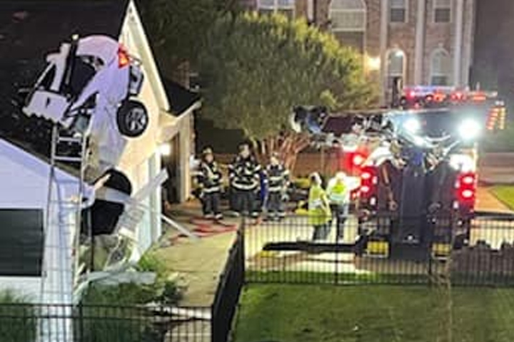 Crews work to remove a car from the roof of a home in Eureka, Missouri, on May 23, 2021.