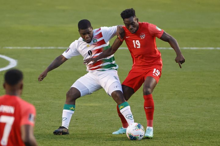 Canada’s Alphonso Davies (19) and Suriname’s Nigel Hasselbaink (9) work for the ball during the first half of a World Cup 2022 Group B qualifying soccer match Tuesday, June 8, 2021, in Bridgeview, Ill.