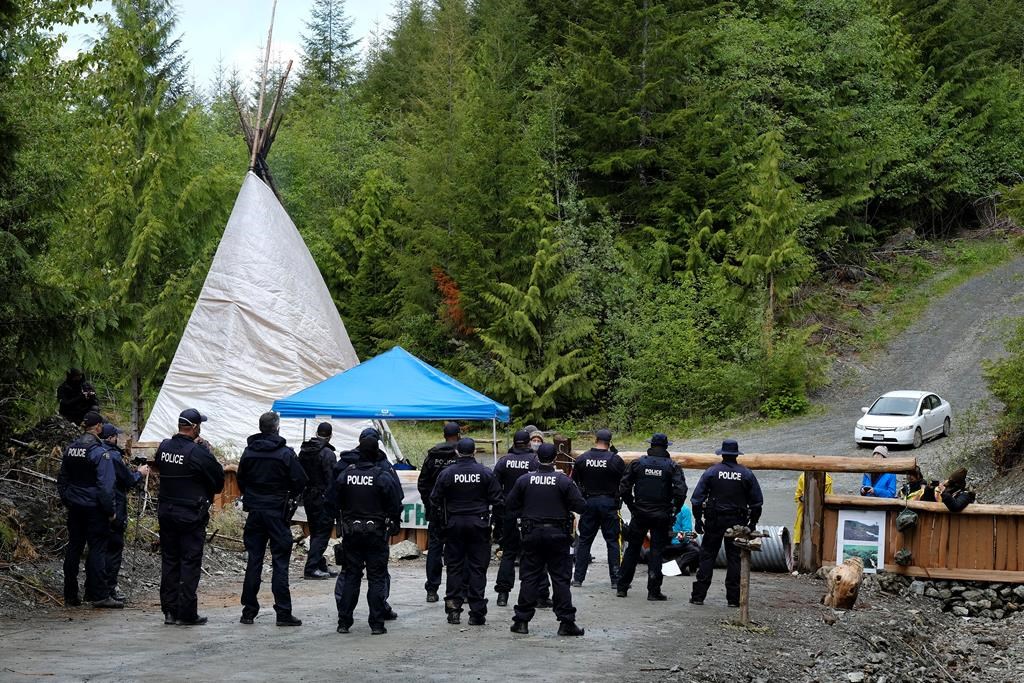 RCMP officers approach an anti-logging blockade in Caycuse, B.C. on Tuesday, May 18, 2021. THE CANADIAN PRESS/Jen Osborne.