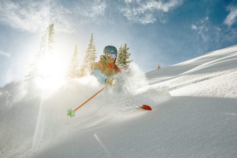 Skier takig a turn in deep powder on a sunny day.