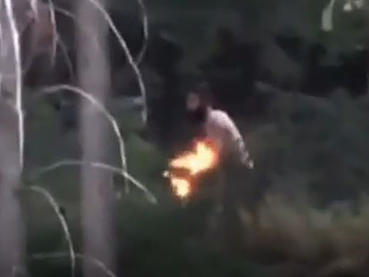 The video was posted to Facebook and shows a shirtless man walking along a steep, bush-covered hill behind a home in West Kelowna.