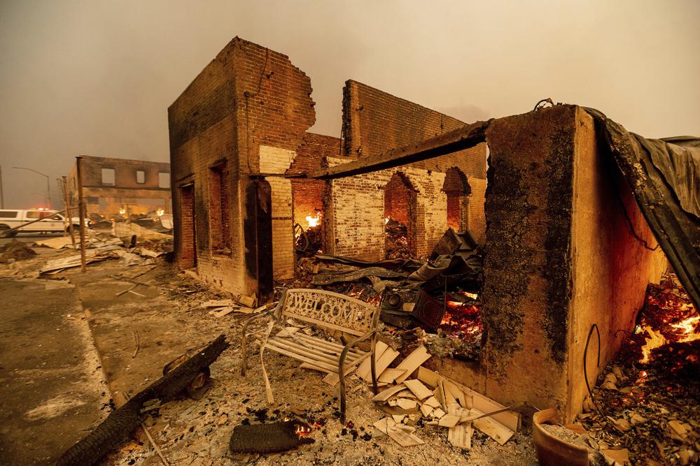 A bench stands outside a scorched building as the Dixie Fire tears through the Greenville community of Plumas County, Calif., on Wednesday, Aug. 4, 2021. The fire leveled multiple historic buildings and dozens of homes in central Greenville.