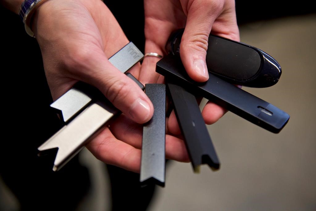 FILE - In this April 16, 2019 file photo, a researcher holds vape pens in a laboratory in Portland, Ore. On Thursday, Sept. 9, 2021, U.S. health officials delayed a high-stakes decision on whether to permit best selling vaping brand Juul to stay on the market, while ordering thousands of other electronic cigarettes off store shelves. (AP Photo/Craig Mitchelldyer, File).