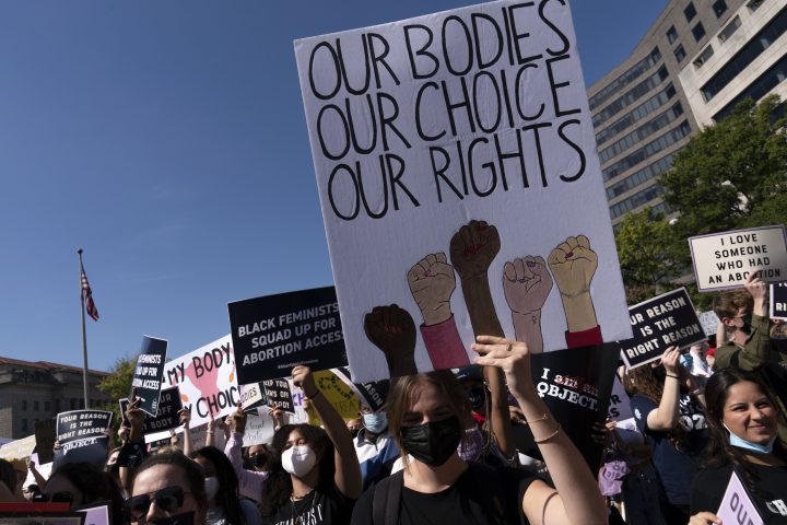 Activists hold signs during the Women’s March rally at Freedom Plaza, in Washington, Saturday, Oct. 2, 2021.