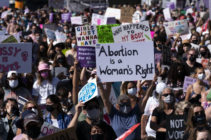 Demonstrators hold signs during the Women’s March rally at Freedom Plaza, in Washington, Saturday, Oct. 2, 2021.