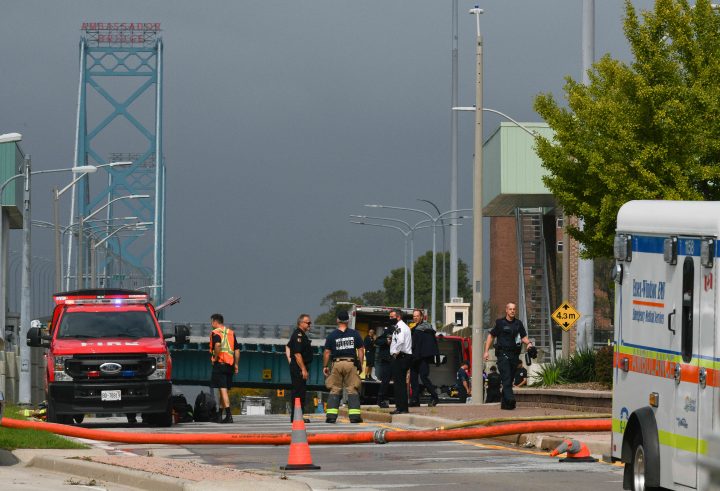Firefighters and officers look on by the Ambassador Bridge border crossing in Windsor, Ont., Monday, Oct. 4, 2021.