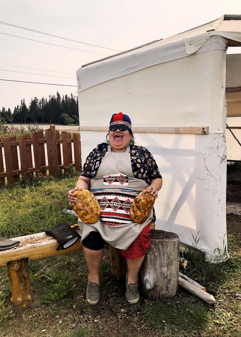 Georgette Mestokosho holds two loaves of bannock that she baked in a sand pit at Ekuanitshit First Nation.