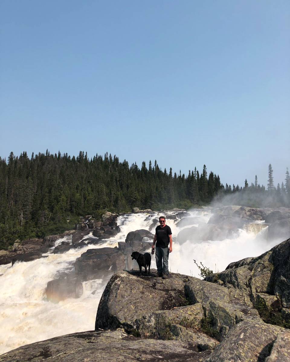 Sylvain Roy and his dog, Katak, stand next to Magpie Falls.